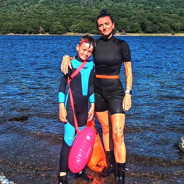 boys wetsuit, color navy and blue, stand beside river with mom